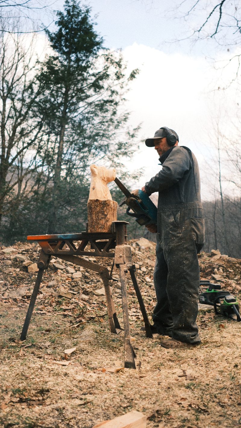 Artisan chainsaw carving a sculpture from salvaged timber