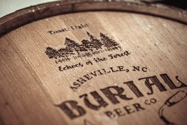 An Echoes of the Forest oak barrel branded with the project logo, crafted from Hurricane Helene–salvaged white oak by Appalachian Cooperage in Marion, North Carolina, in collaboration with Burial Beer Co.'s Tim Gormley for the Echoes Oak Aged Brown Ale