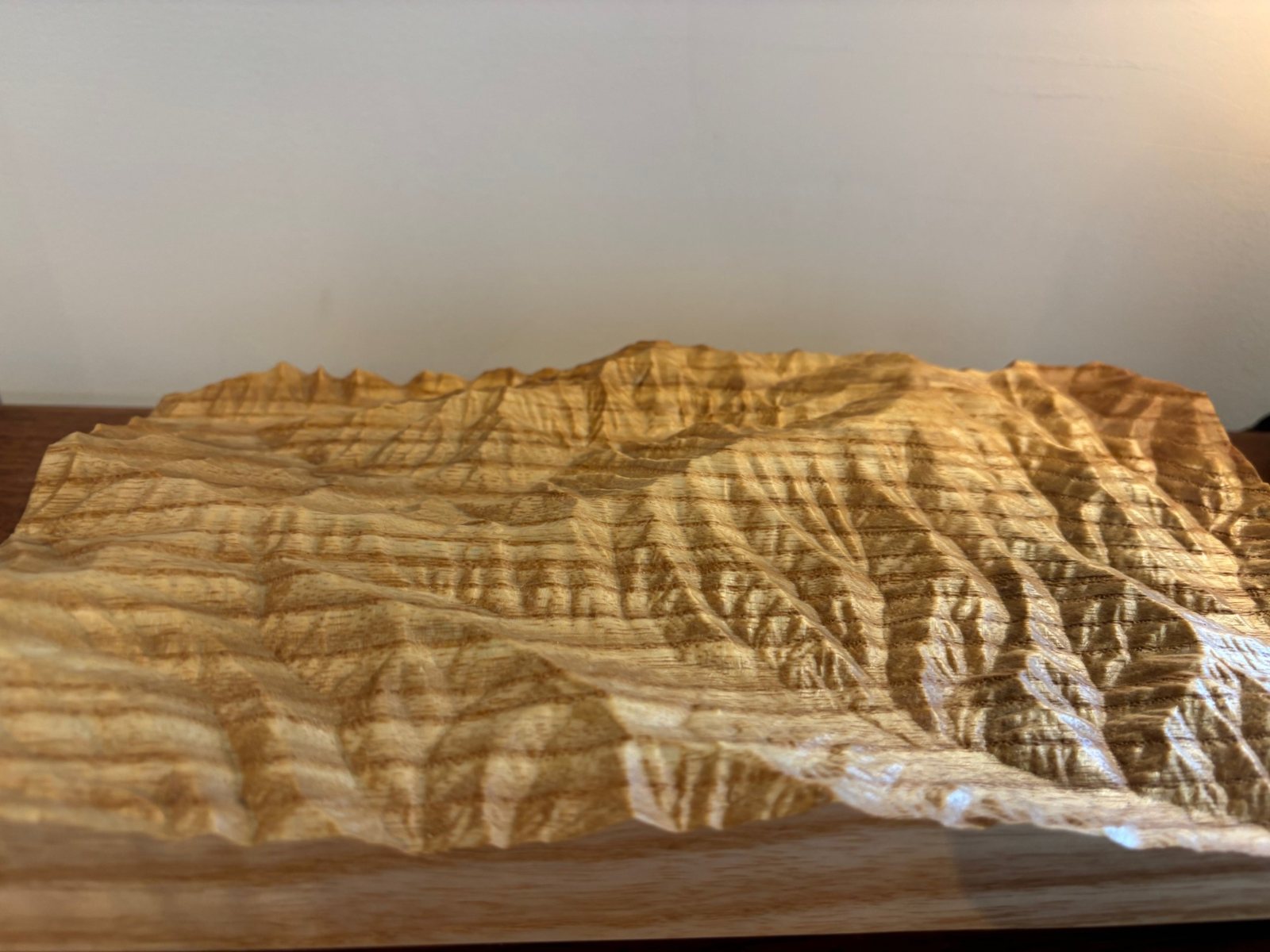 A topographic mountain sculpture carved from Helene salvaged wood by Mickey Strivelli, with ridgelines and valleys cut into the grain