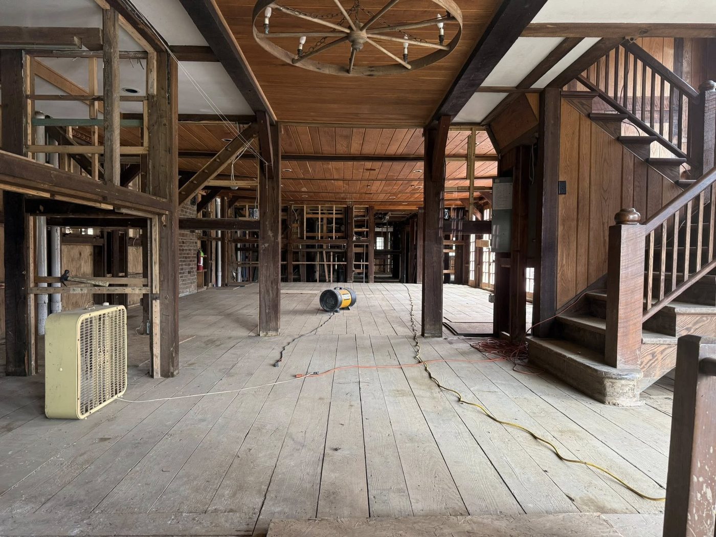 The gutted interior of the Celo Inn — exposed framing, bare floorboards, and industrial fans drying out the structure after Helene's floodwaters receded