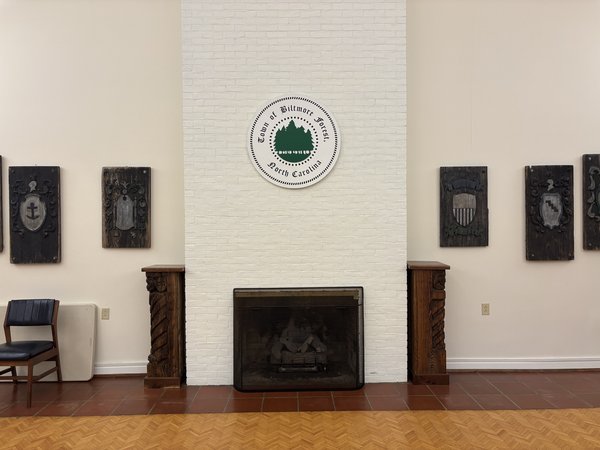 The Town Hall fireplace before the mantel, white brick chimney with the town seal above and carved wooden panels on either side