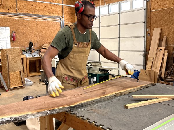 Kwadwo Som-Pimpong measuring a live-edge black walnut slab in his workshop