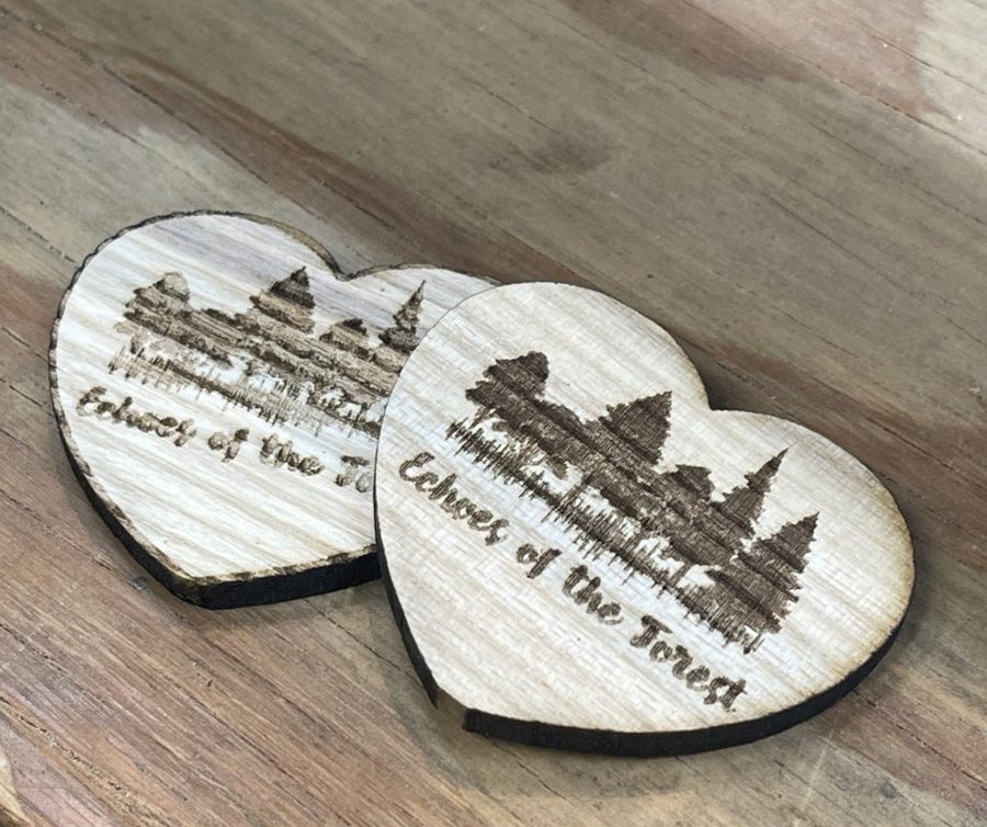 Two heart-shaped pieces of wood laser-engraved with the Echoes of the Forest mark and a Western North Carolina mountain skyline