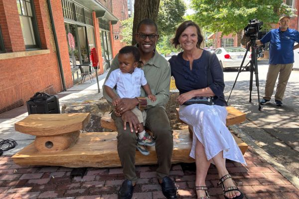 A family seated on the white oak bench at the YMI Cultural Center, unveiled on Juneteenth