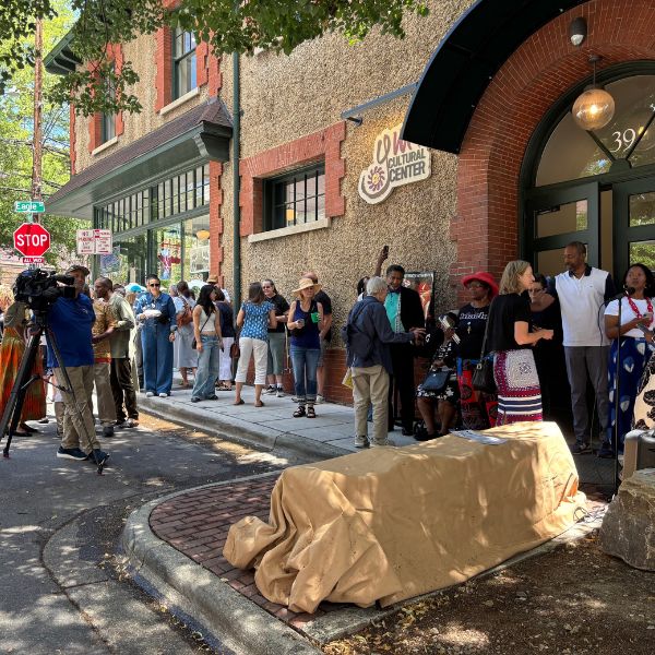 A crowd gathers outside the YMI Cultural Center before the unveiling, the bench still under a canvas cover