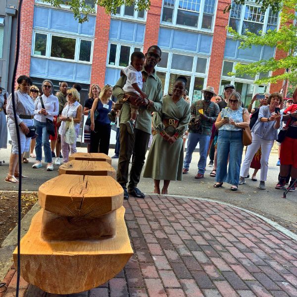 The newly unveiled white oak bench with the crowd gathered behind it