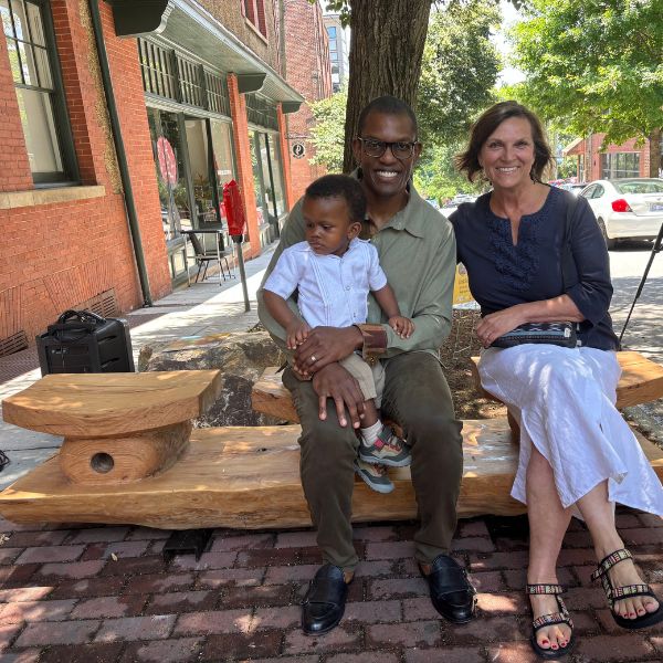 A family seated together on the new bench beneath the tree