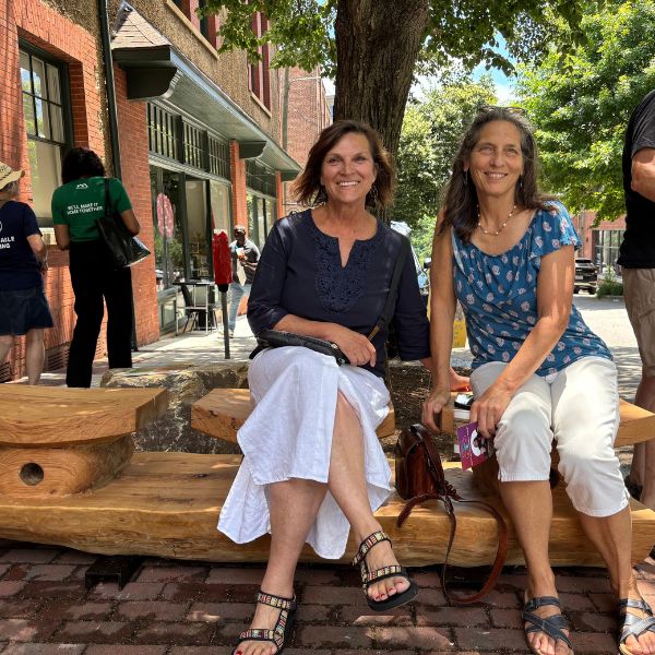 Two visitors seated on the bench in the shade