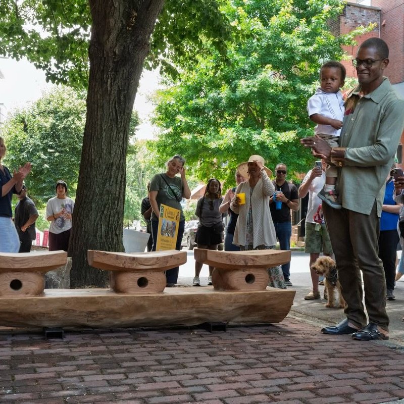 The newly unveiled white oak bench at the YMI Cultural Center as the crowd applauds on Juneteenth