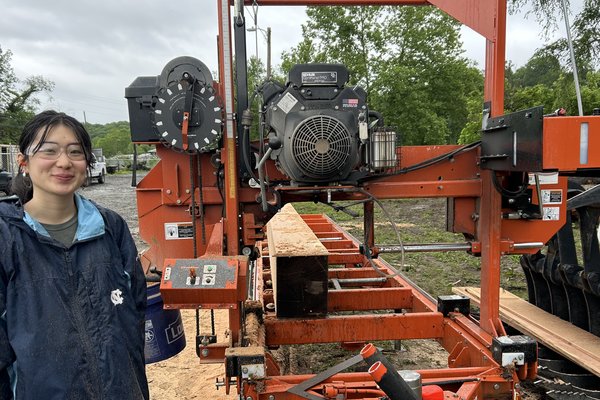Echoes intern Lydia Xu beside the portable sawmill at UNC Asheville