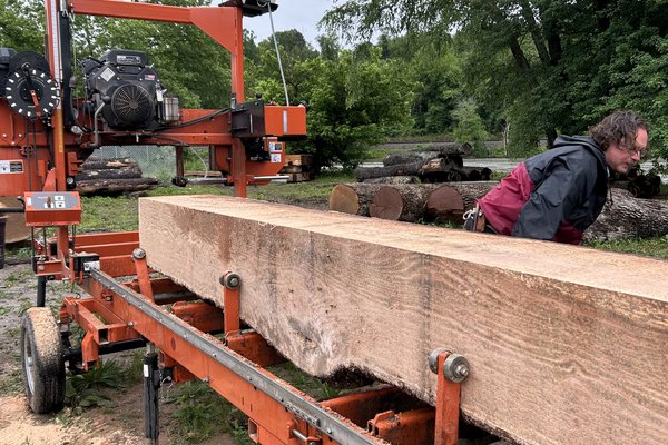 A freshly milled slab of salvaged timber rests on the bed of the portable sawmill at UNC Asheville, its pale grain exposed