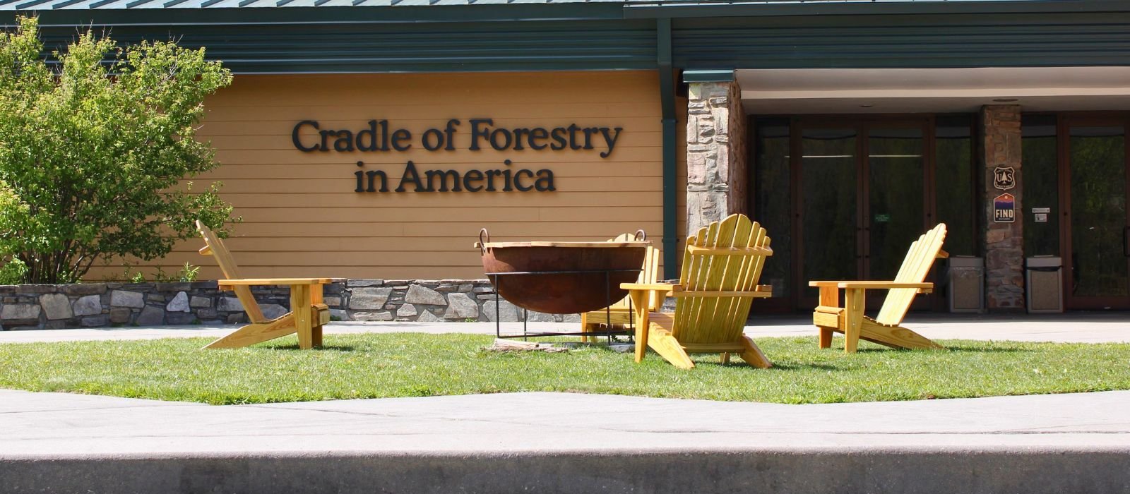 The Cradle of Forestry in America visitor center in Pisgah National Forest, with wooden Adirondack chairs arranged on the lawn out front