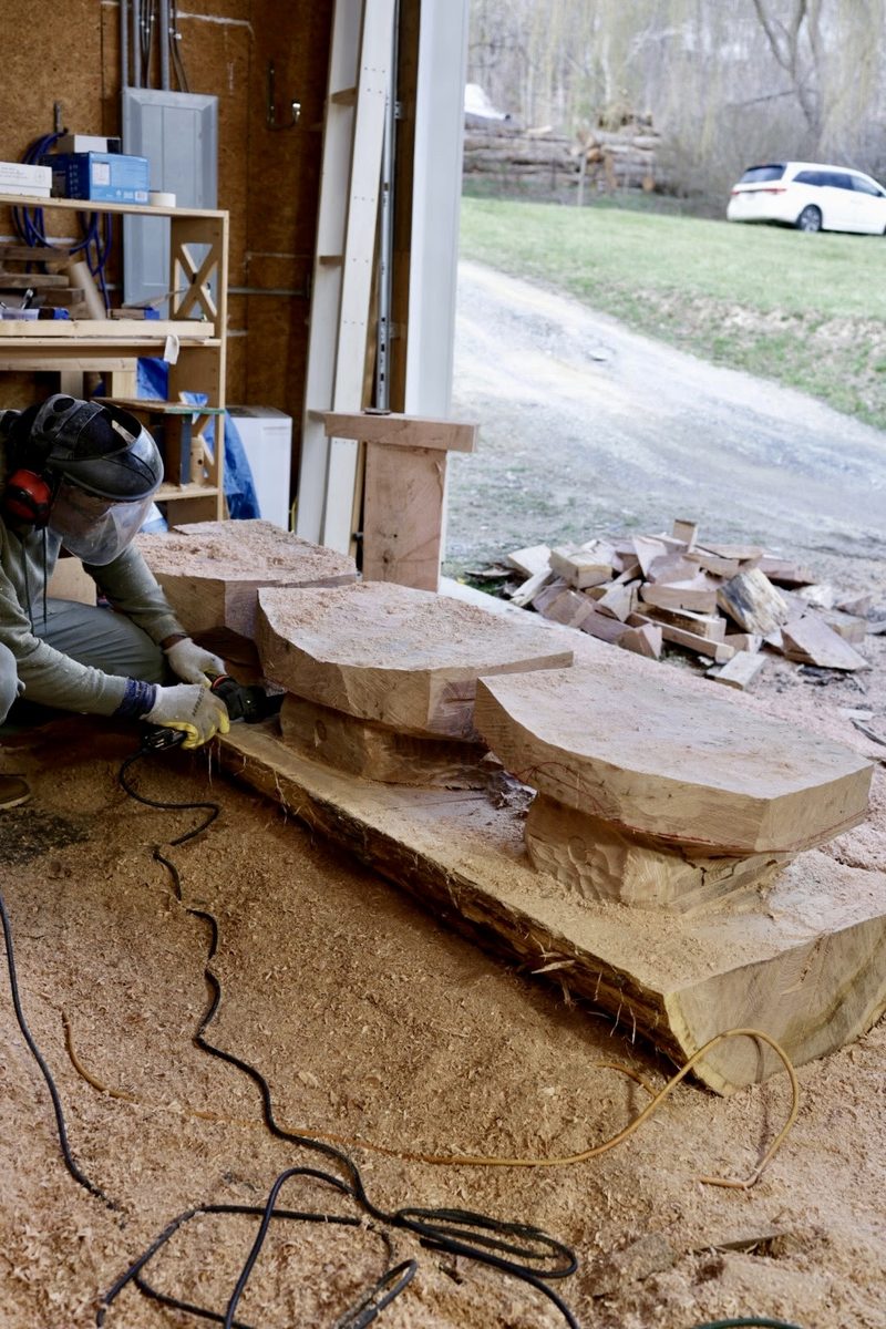 Artisan carving salvaged timber into an Echo installation