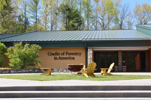 Cradle of Forestry in America visitor center, with wooden Adirondack chairs out front in Pisgah National Forest