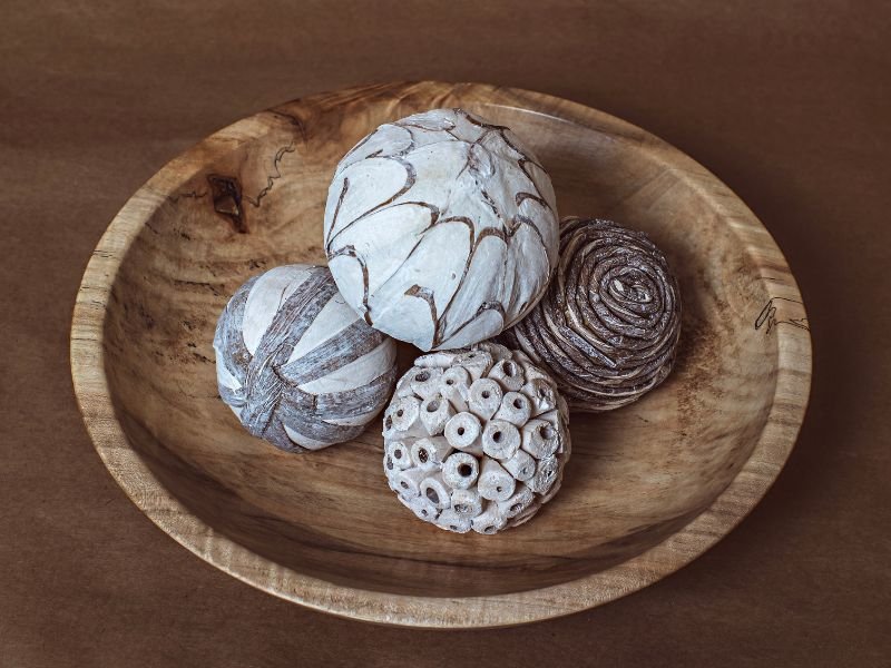 Hand-turned wooden bowl holding decorative carved spheres